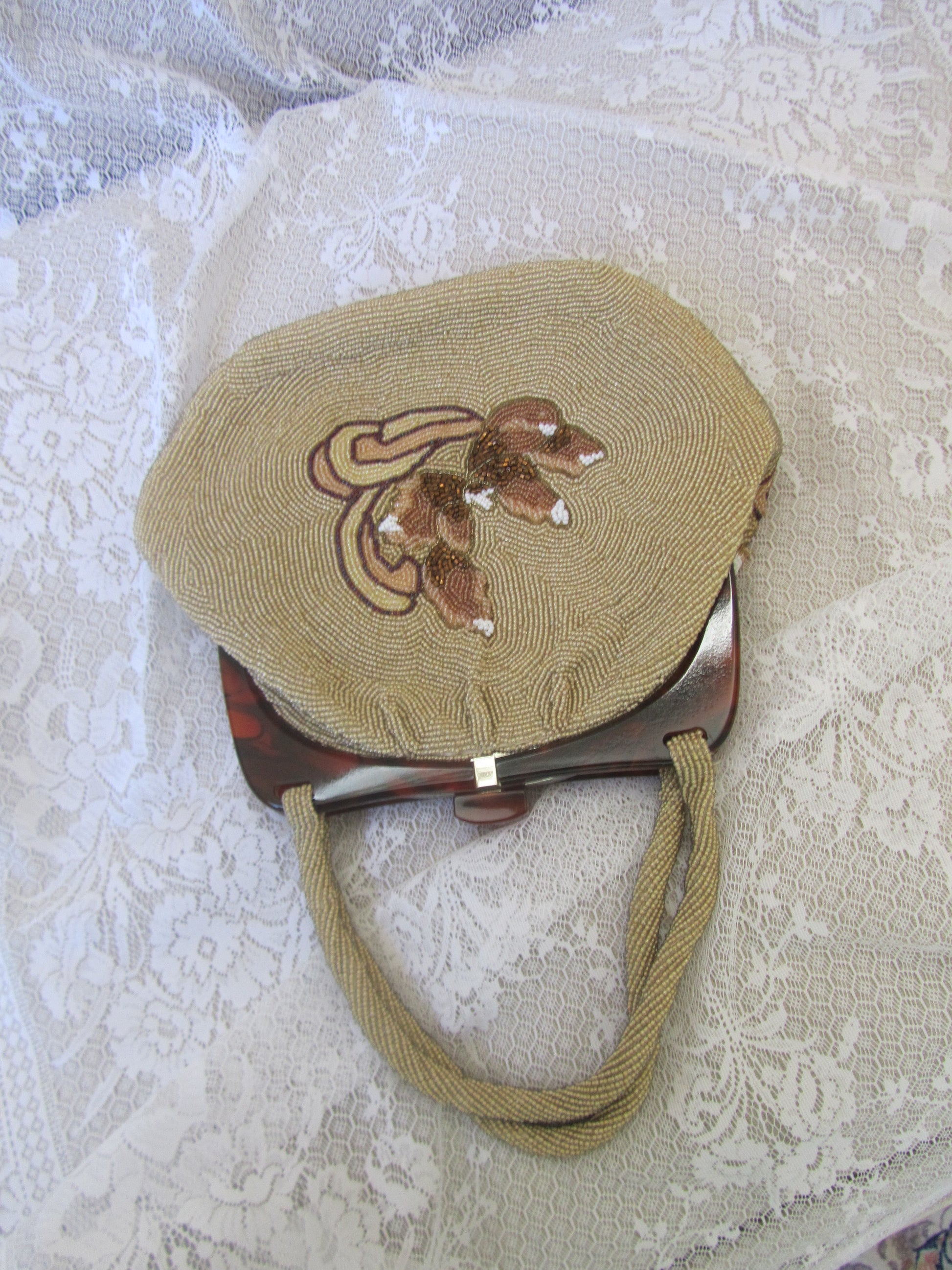 Round embroidered bag with a handle on a textured white background