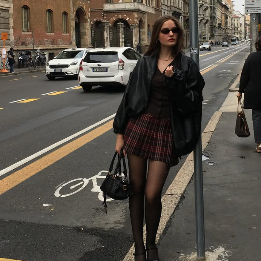 Woman standing on a city street with buildings and traffic in the background