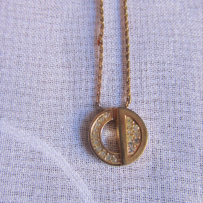 Gold necklace with a round pendant on a light fabric background