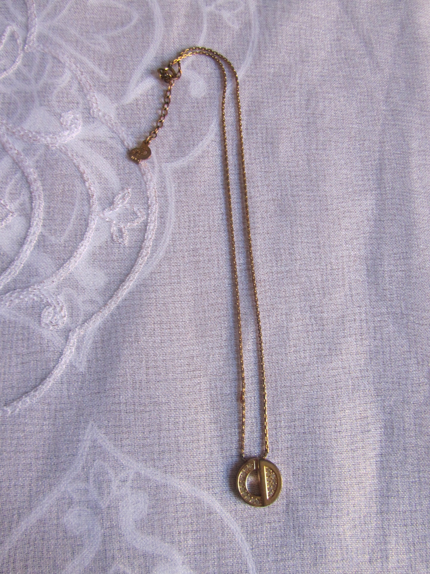 Gold necklace on a textured light gray fabric background