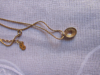 Gold necklace with a pendant on a light gray fabric background