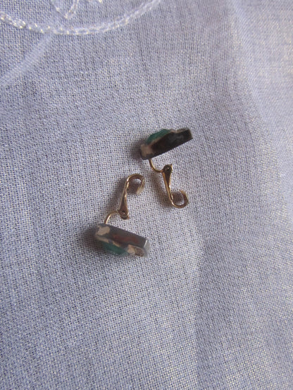 Gold earrings on a textured gray fabric background