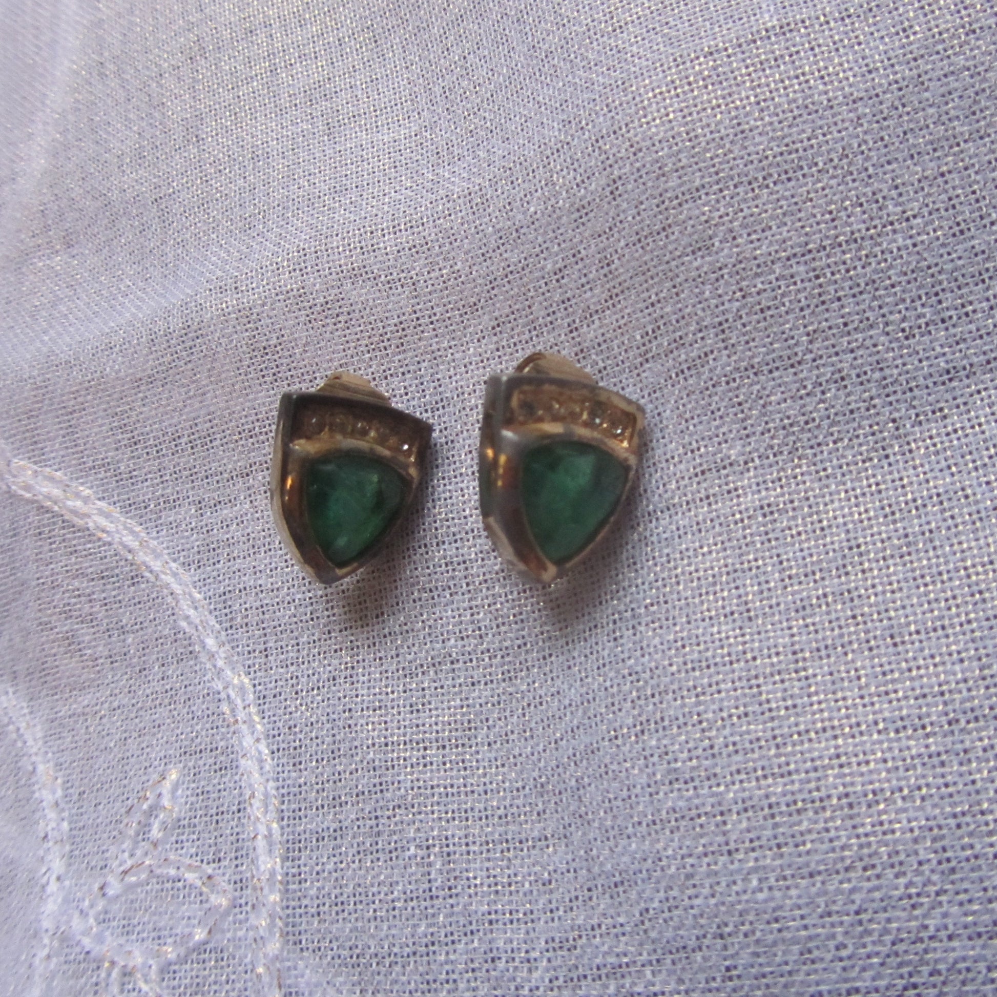 Pair of earrings with green stones on a light fabric background