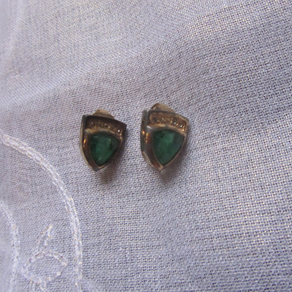 Pair of earrings with green stones on a light fabric background