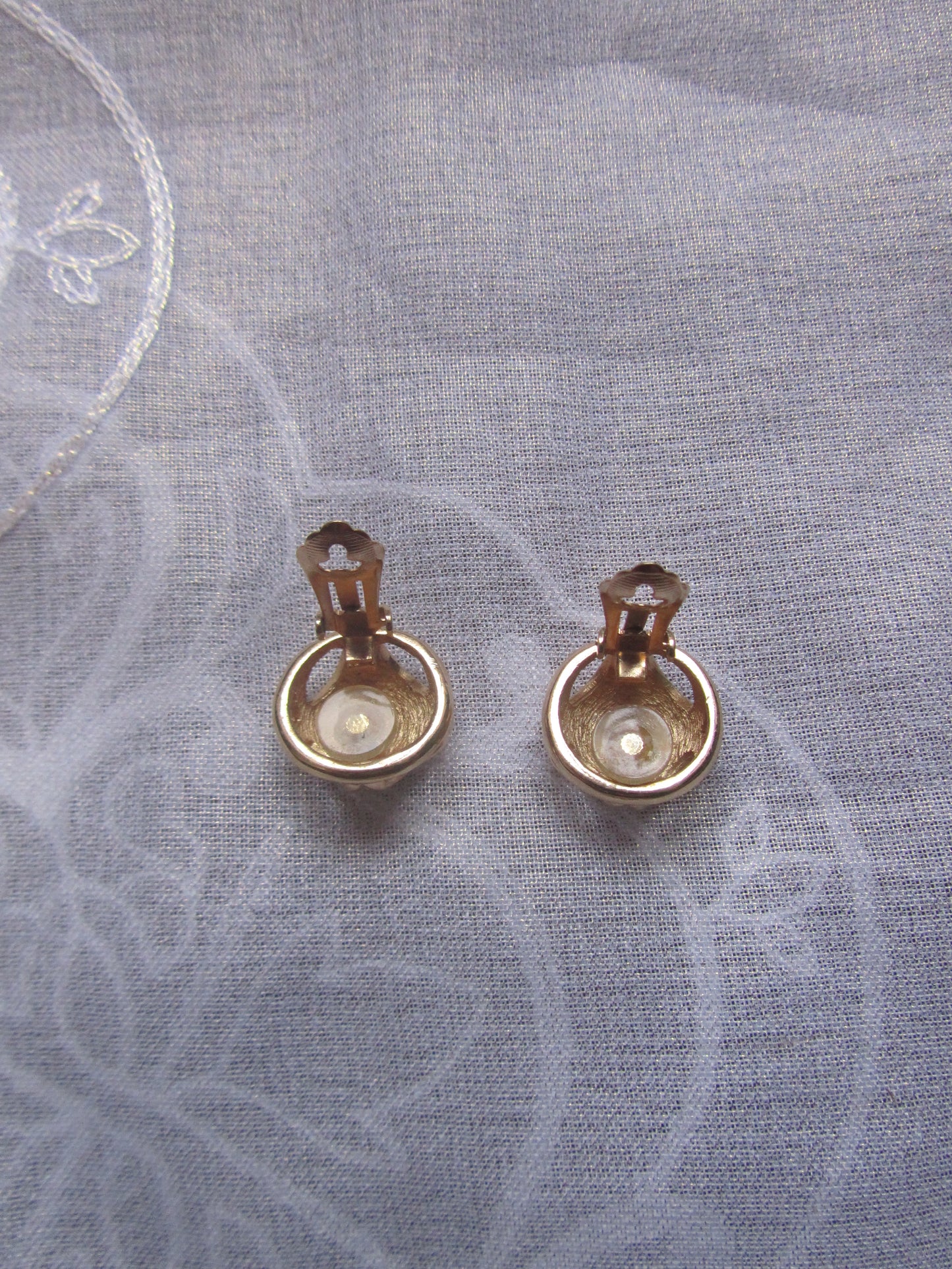 Pair of gold earrings on a textured gray fabric background