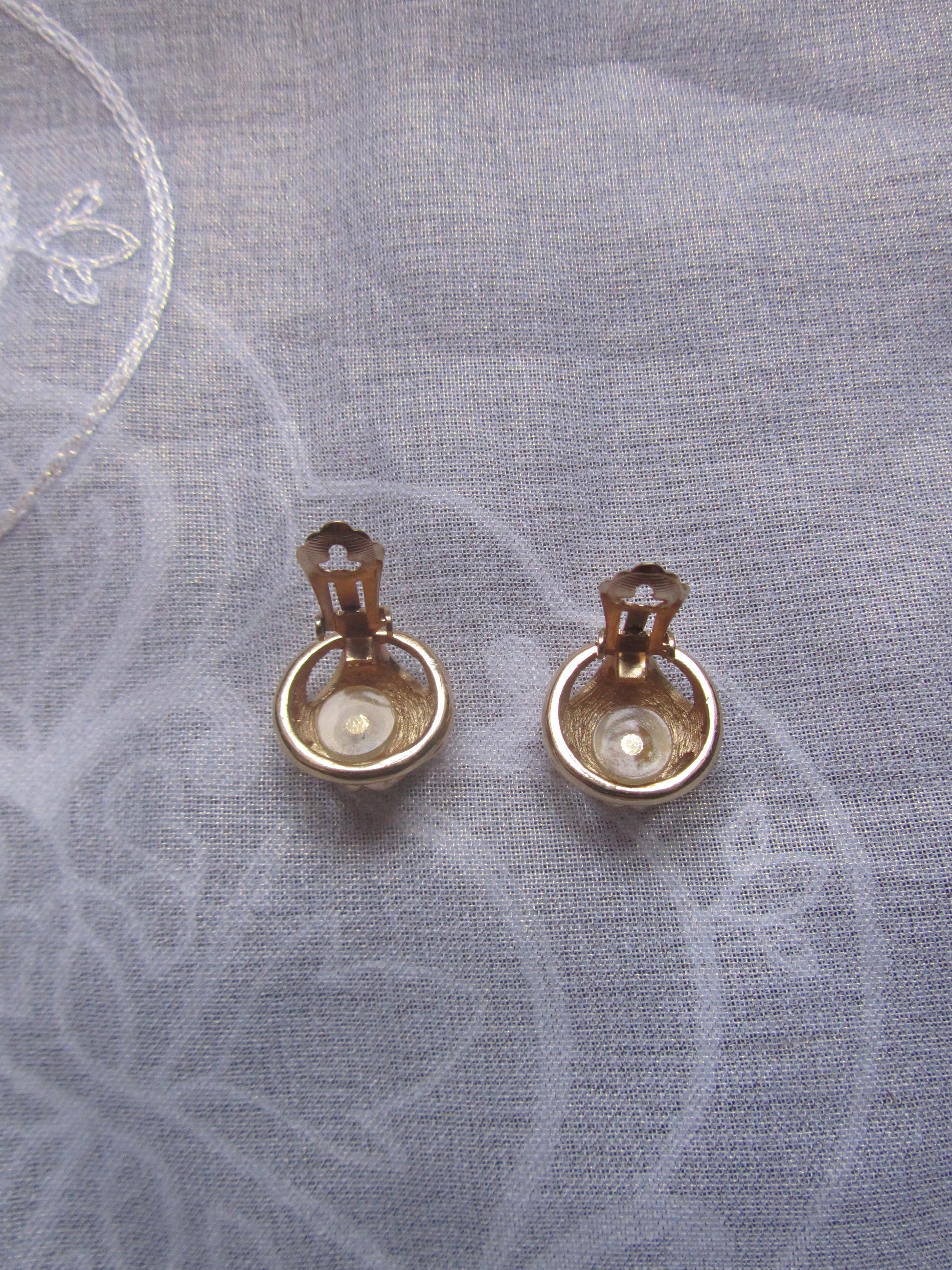 Pair of gold earrings on a textured gray fabric background