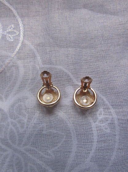 Pair of gold earrings on a textured gray fabric background
