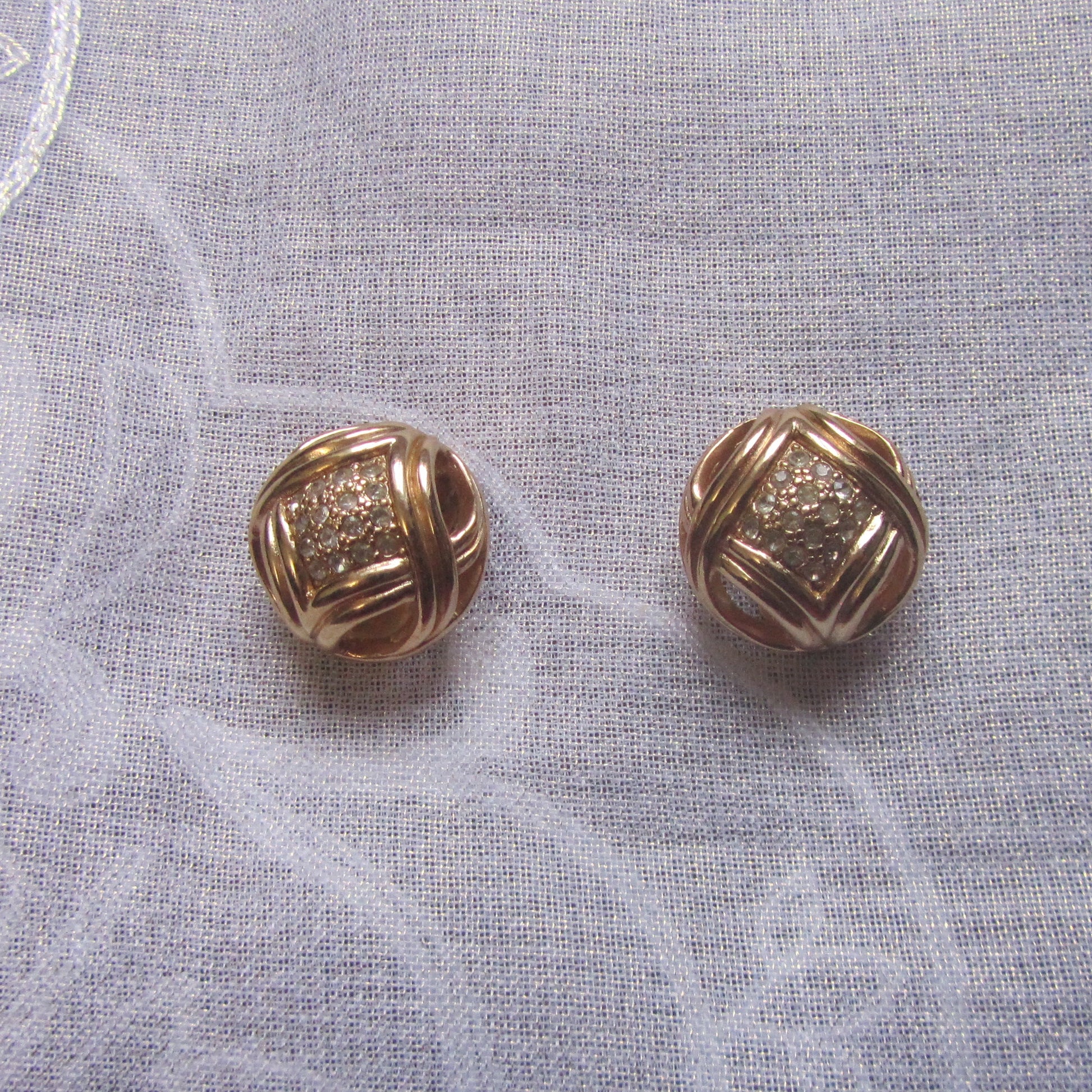 Pair of gold earrings on a textured white fabric background