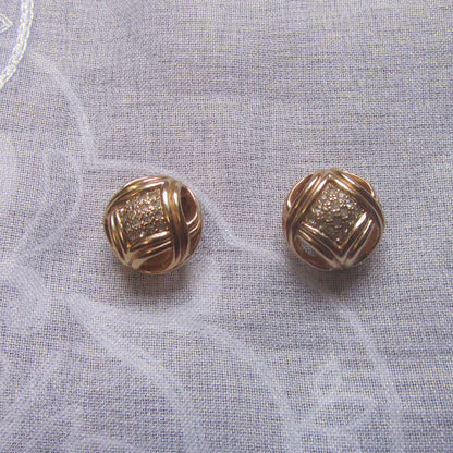 Pair of gold earrings on a textured white fabric background