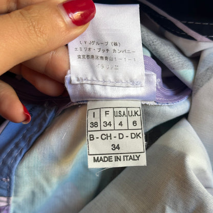 Clothing tag with size and brand information held by a hand.