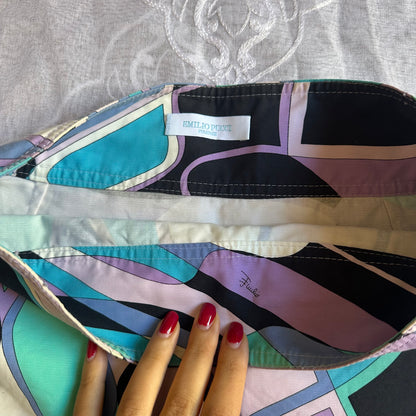 Colorful geometric-patterned fabric with a hand holding it, showing brand labels.