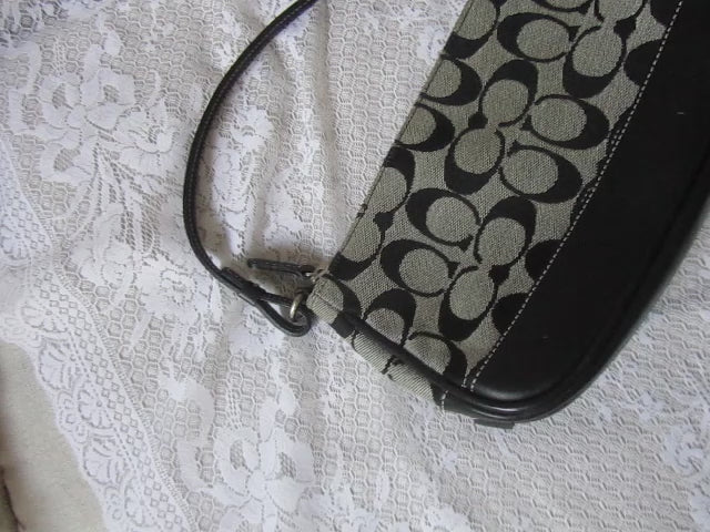Coach handbag with black and beige pattern on a textured white surface
