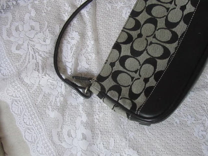 Coach handbag with black and beige pattern on a textured white surface
