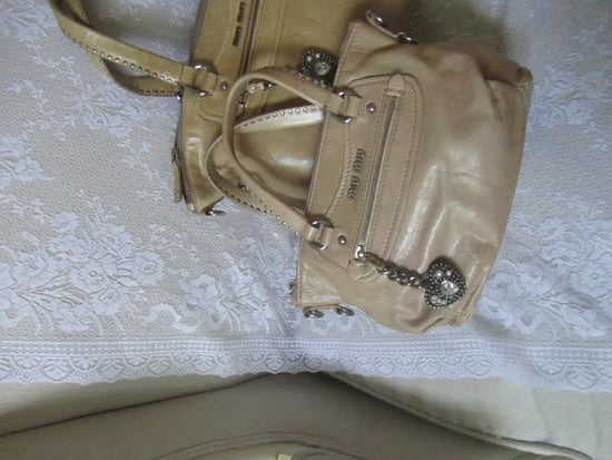 two handbags with heart charm detailing on a textured white surface