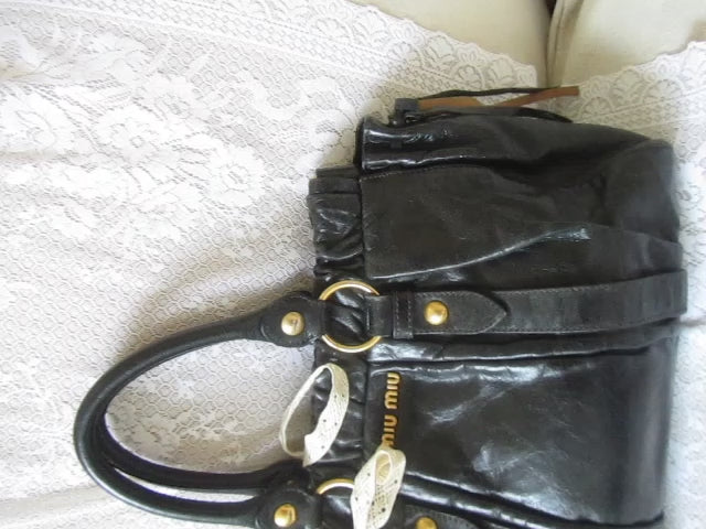 Black handbag with gold accents on a textured white surface
