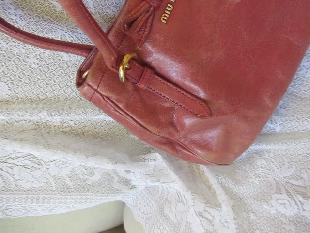 pink leather handbag on a textured beige surface
