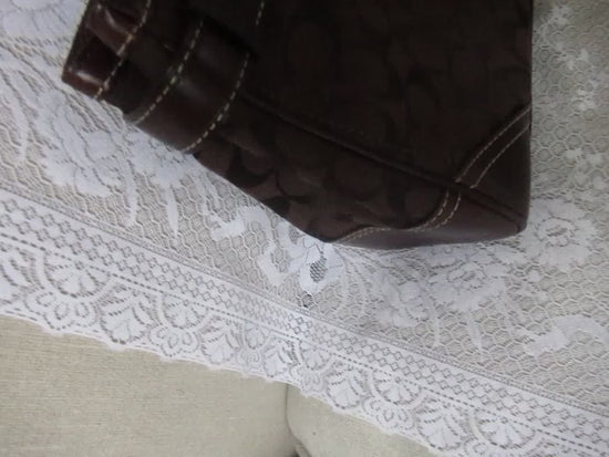 Brown handbag with a visible brand logo on a white textured surface