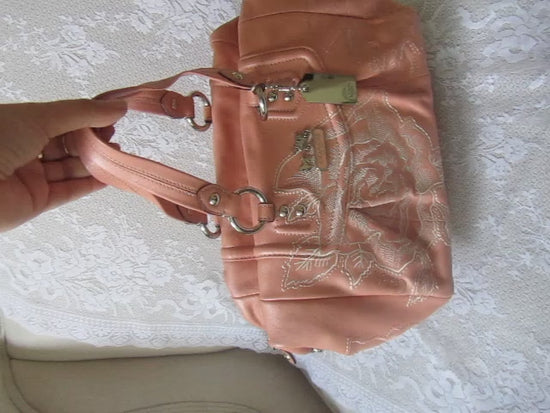 Pink handbag with lace detailing on a textured white surface