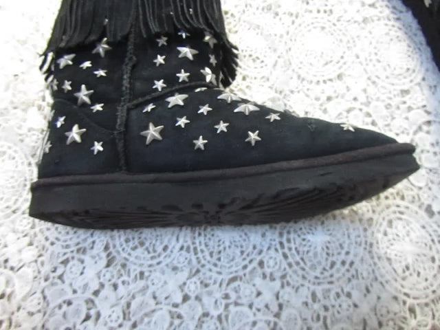 Black boots with white star patterns and fringes on a textured surface