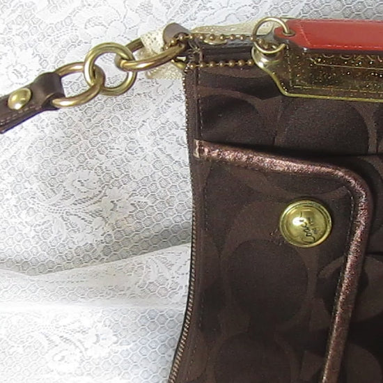 Brown textured handbag with gold accents on a white lace background