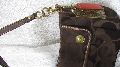 Brown textured handbag with gold accents on a white lace background